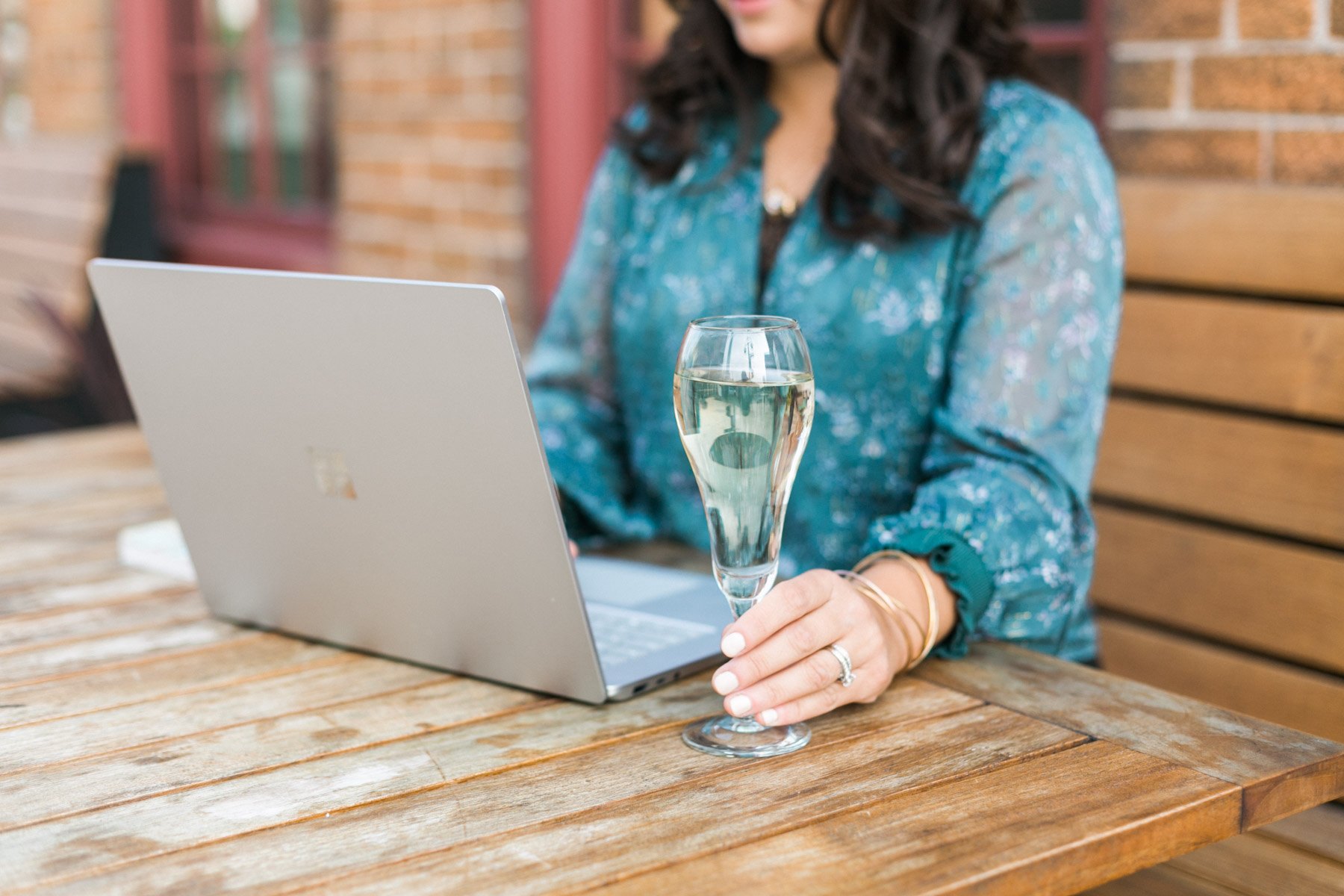 woman working on a laptop at patio restaurant with champagne