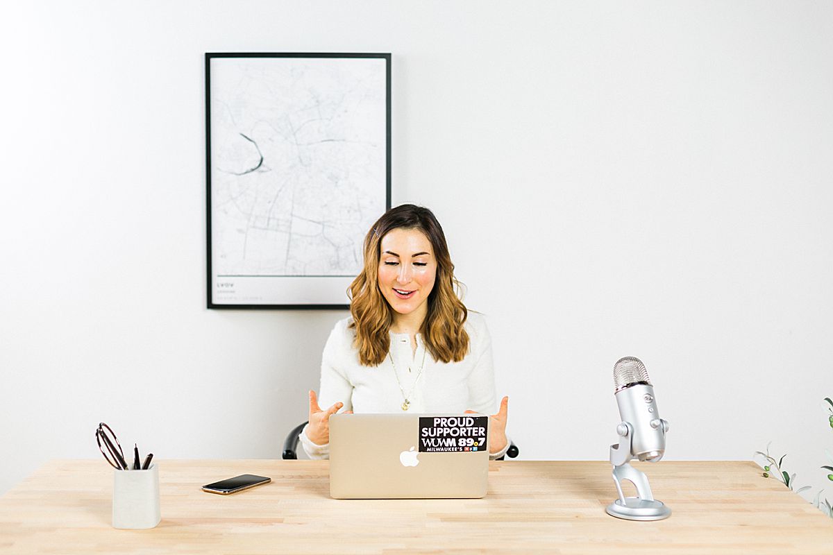 woman business coach working at laptop and minimalist desk with microphone