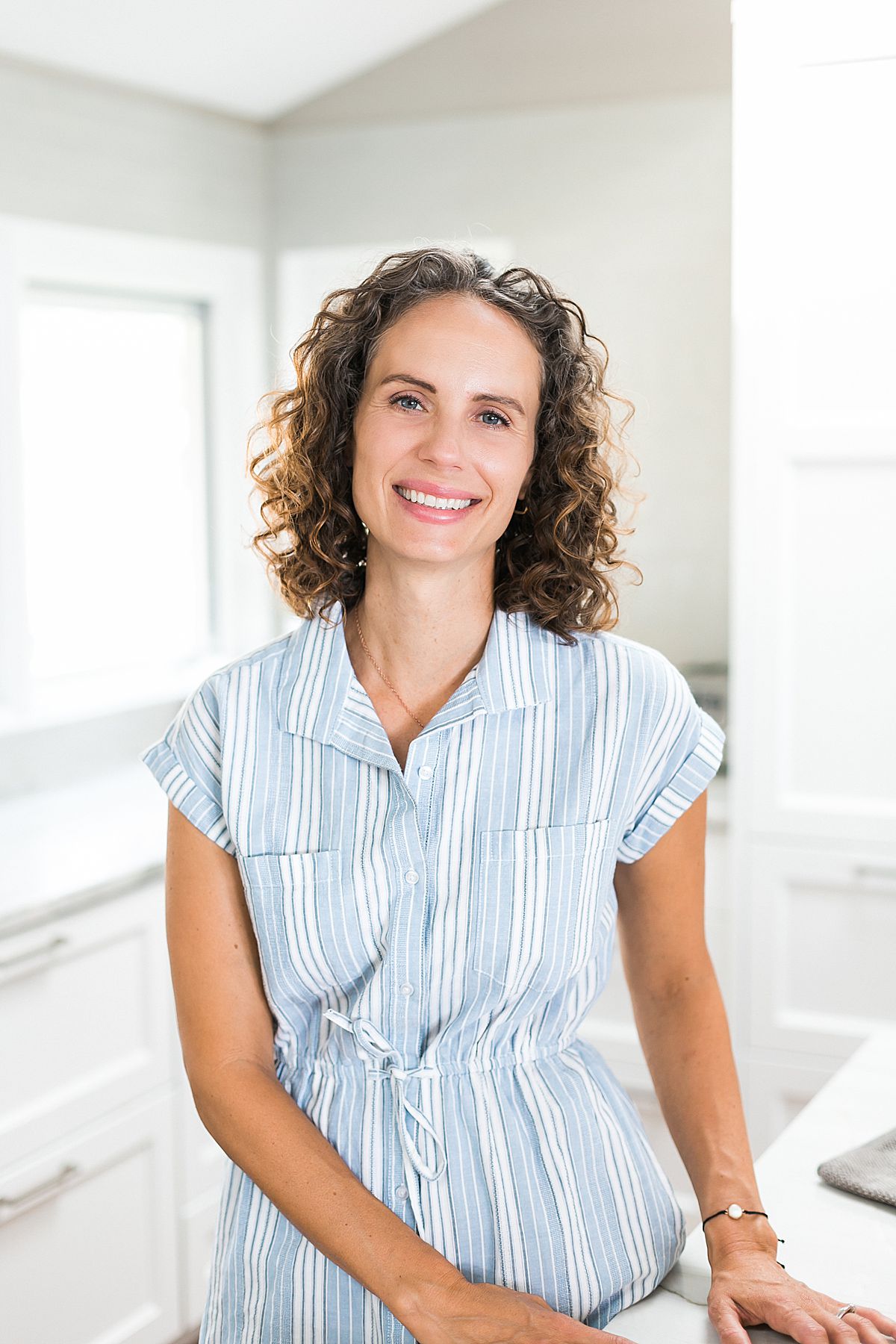 woman standing for a headshot in a bright modern white kitchen