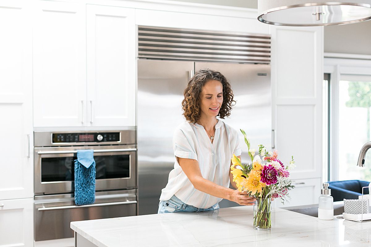woman in kitchen with vase of flowers