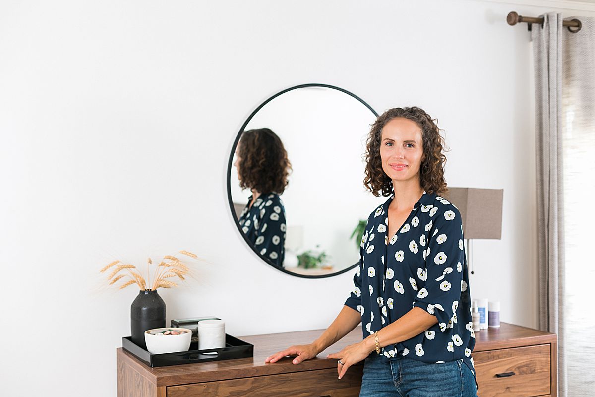 woman next to round mirror and bedroom dresser