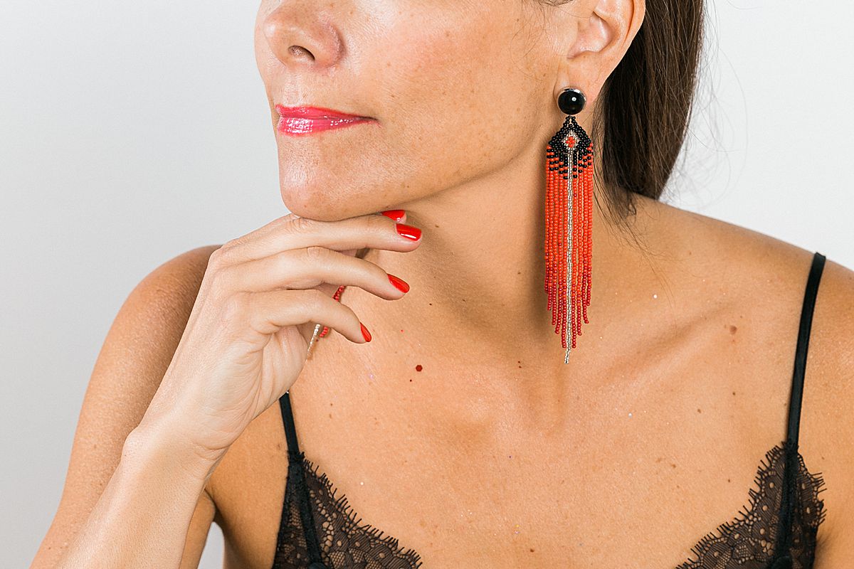 woman with long red feather shaped earrings