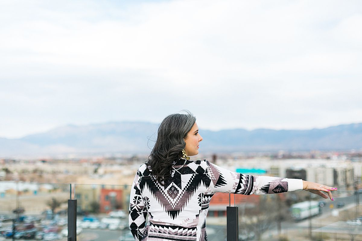 woman in southwest pattern dress with city and mountains in the background