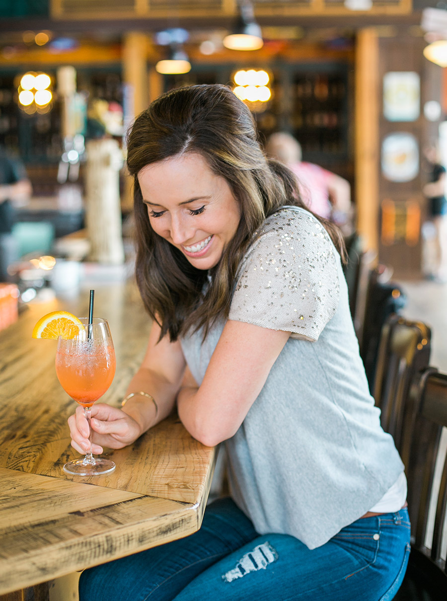marketing coach, woman brand headshot laughing at a bar with a cocktail in hand