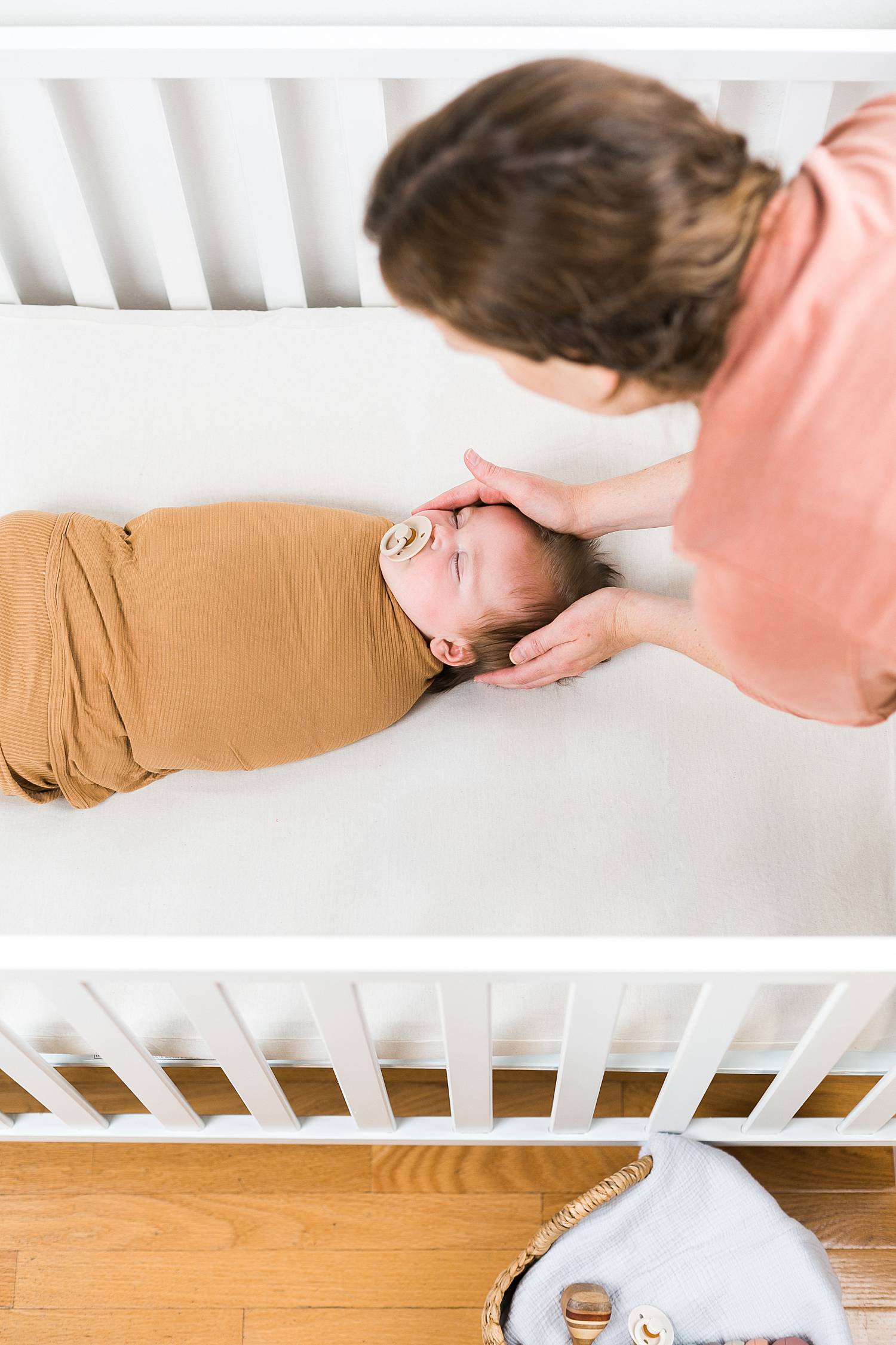 woman placing newborn baby in crib, sleep consultant