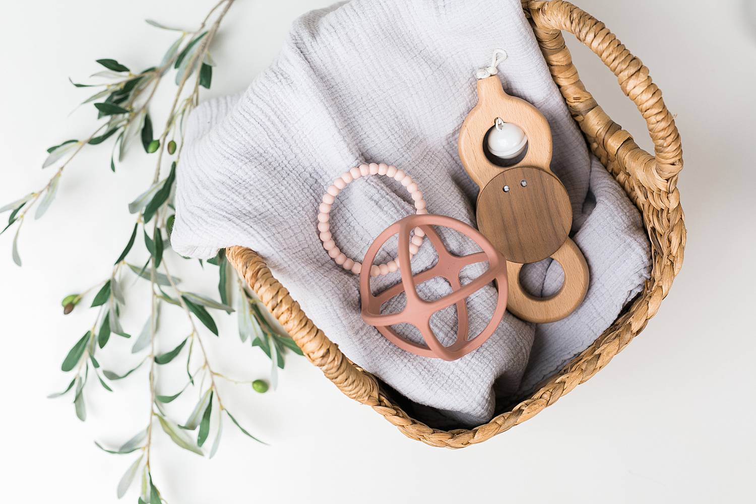 toys in a basket, boho feel with wooden toys and olive tree stem in the background