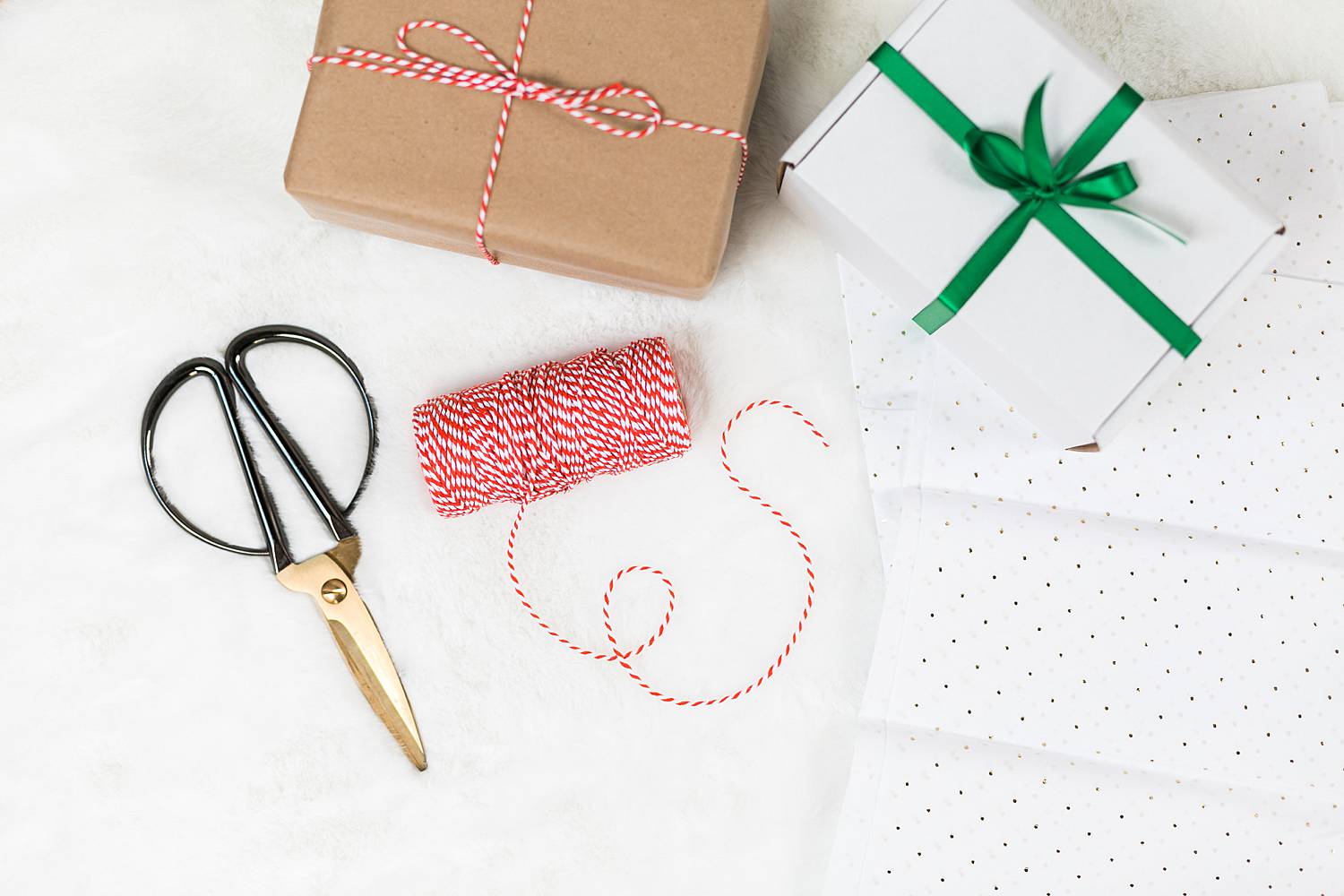 holiday gifting with scissors, twine, and wrapped gifts on a white background