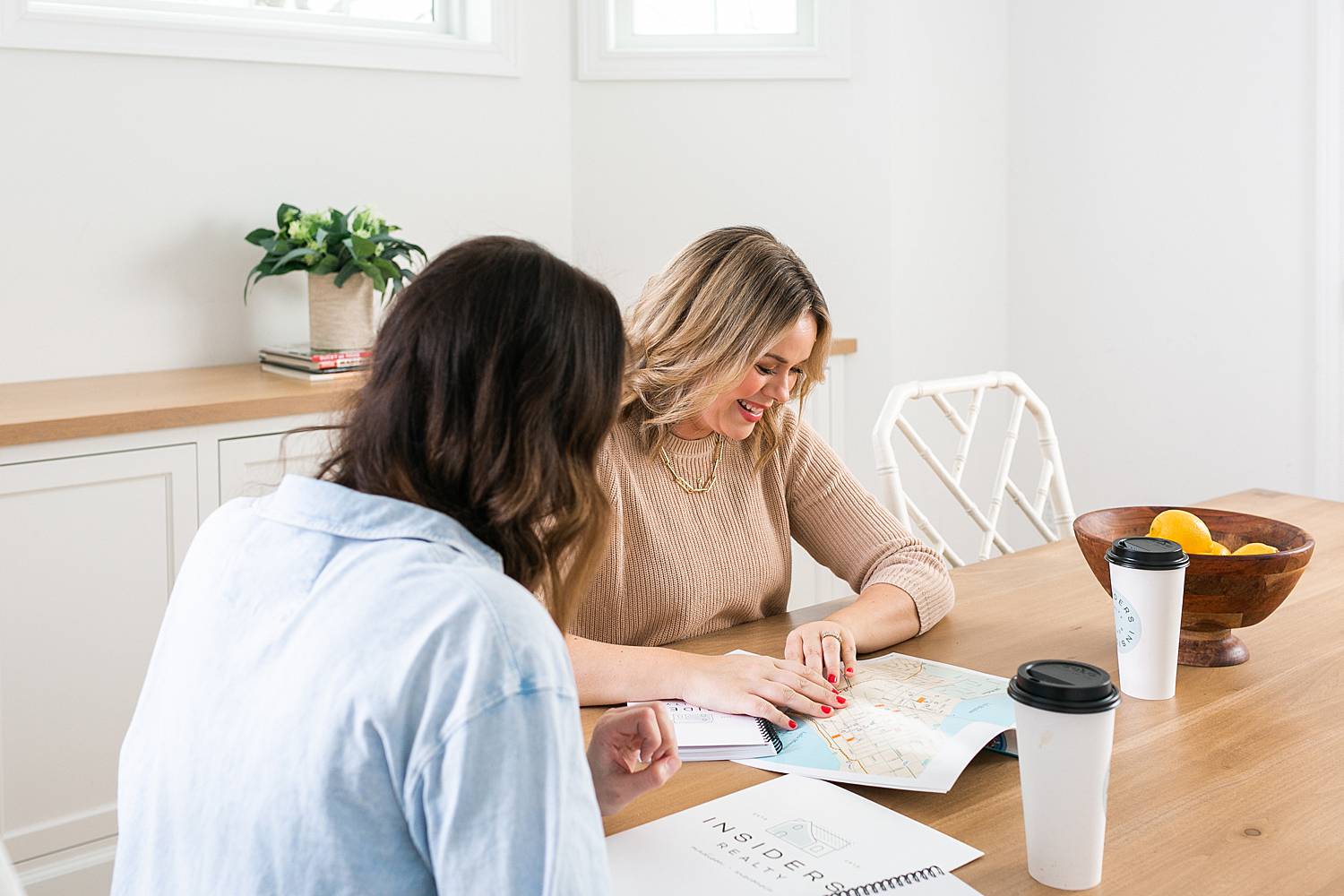 two women real estate agents working at wooden tabletop with coffee and notebooks