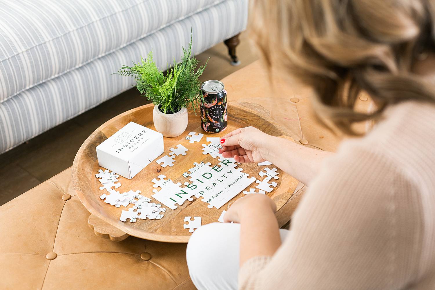 woman putting together custom branded insiders realty puzzle at coffee table in living room