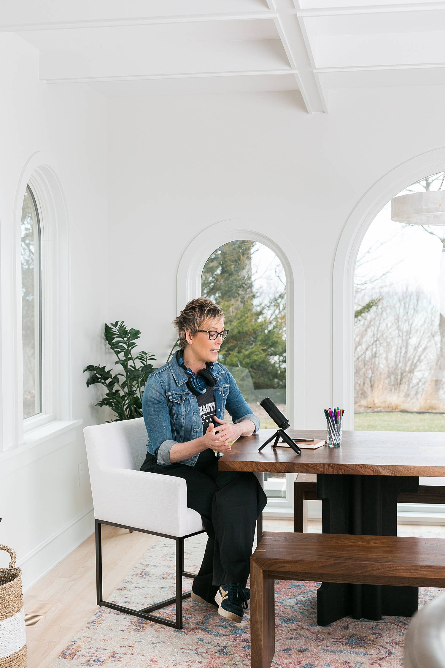 woman podcasting in a bright white room with arched windows
