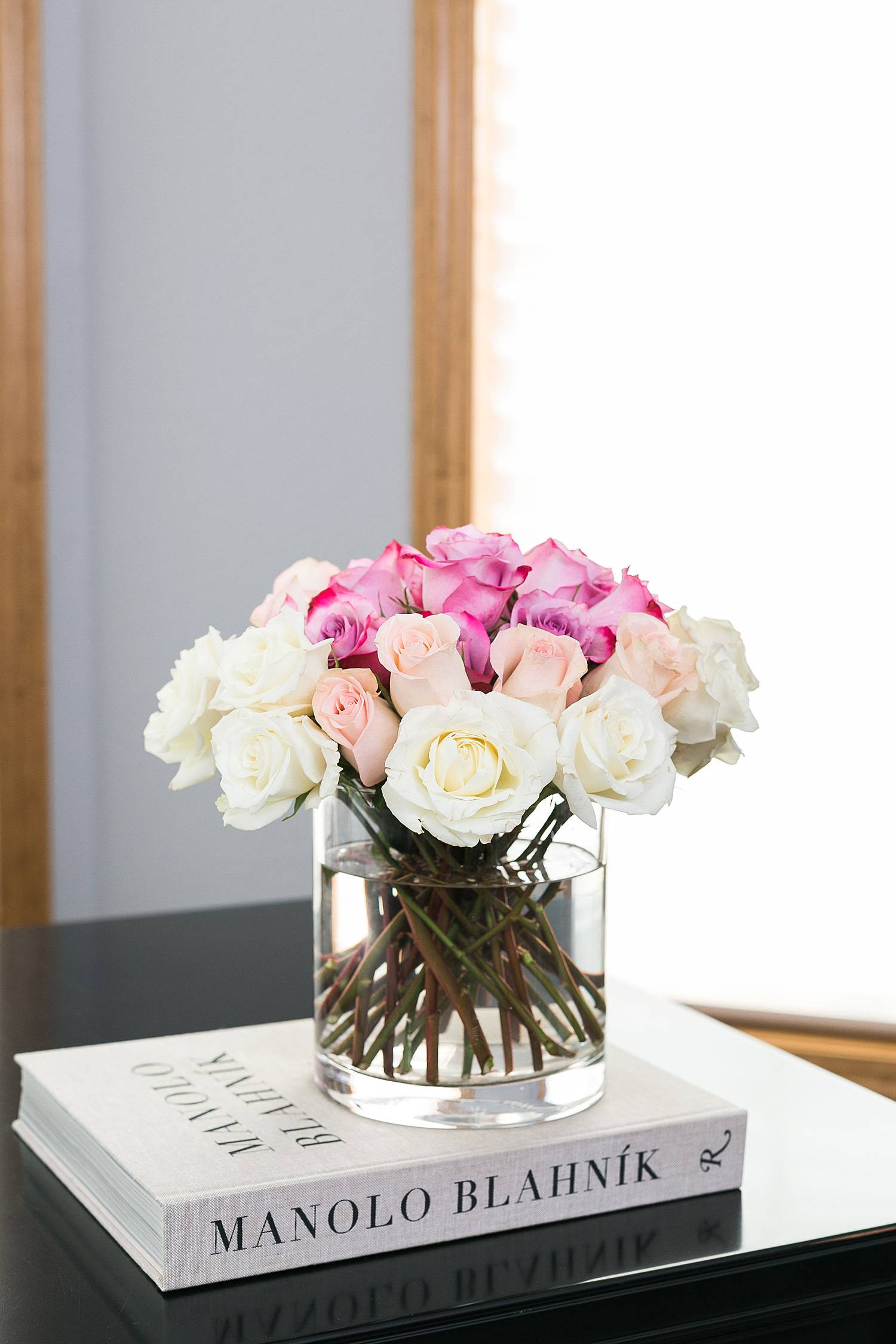 bouquet of white and pink roses on top of manolo blahnik fashion book