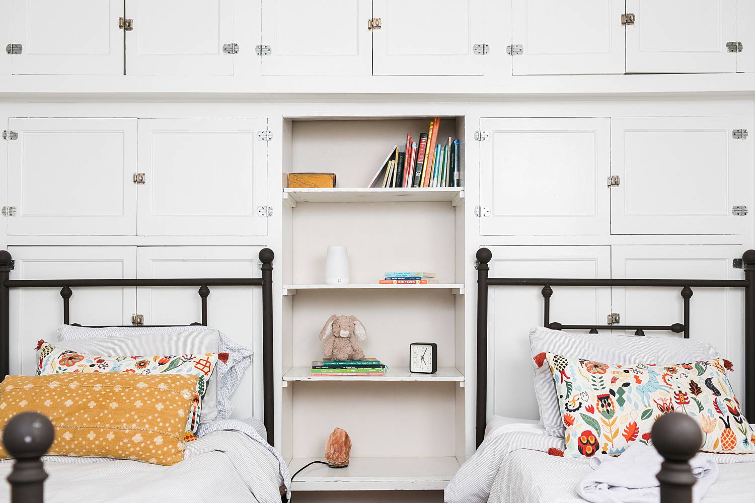 toddler bedroom with white cabinet shelves and colorful pillows