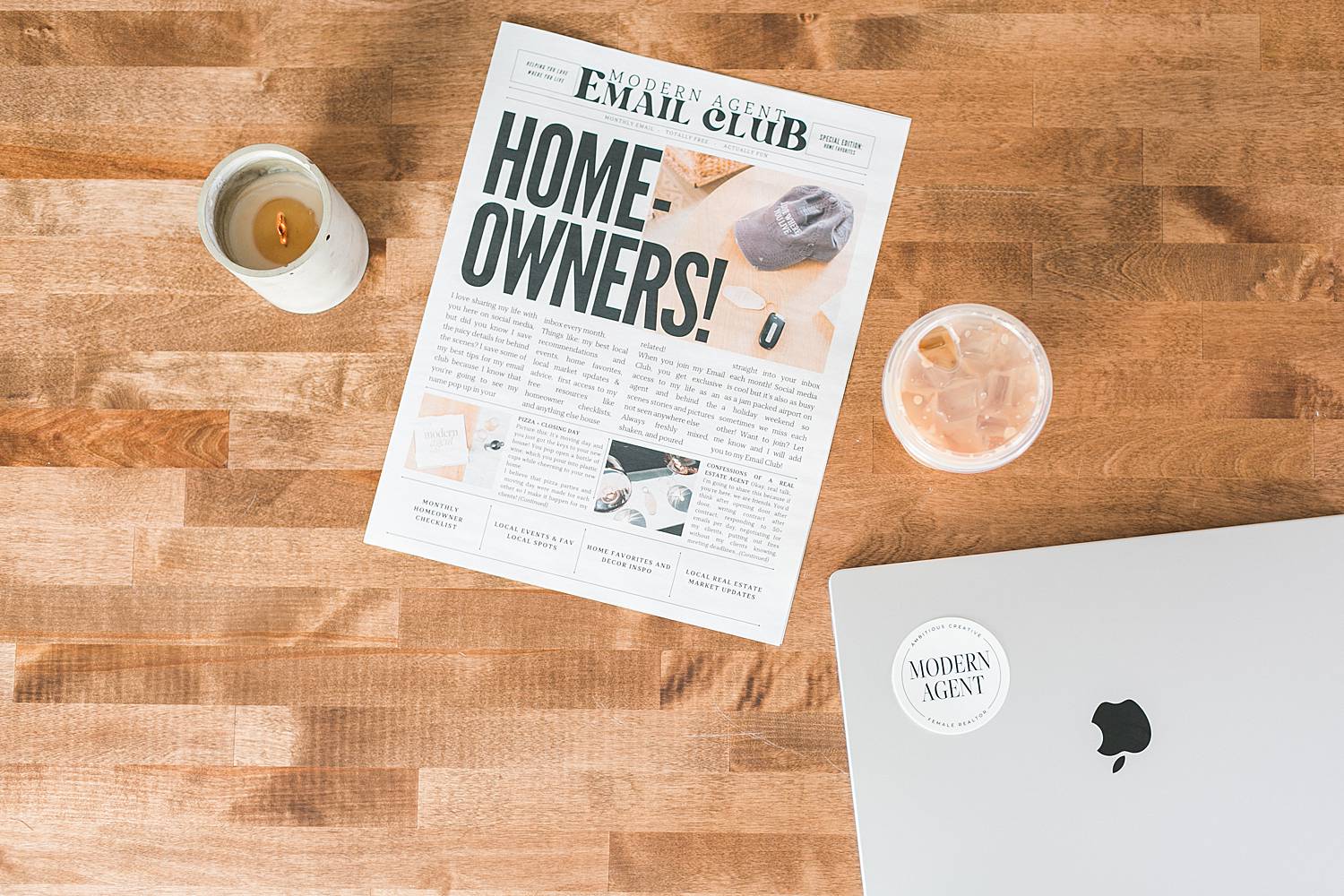 laptop and candle and newspaper for real estate agents on a wooden table