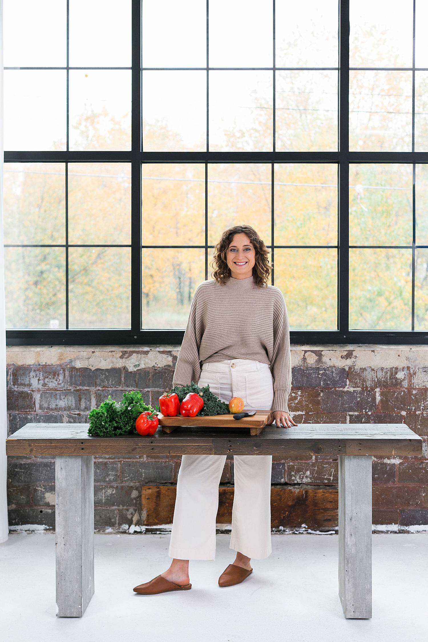 woman with fresh produce vegetables at a cutting board side table