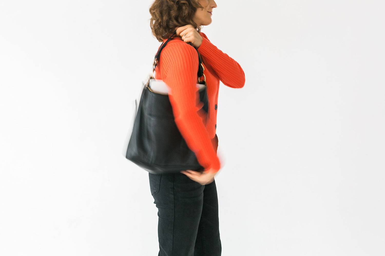woman in red orange sweater putting on a bag
