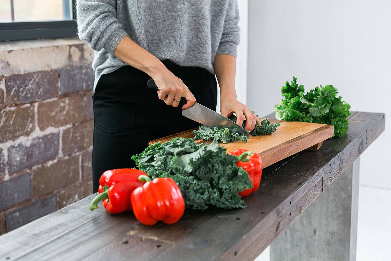 woman chopping produce kale and peppers