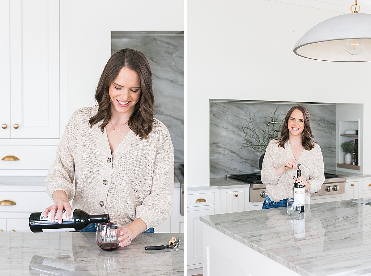 woman in tan neutral sweater pouring a glass of red wine in modern aesthetic kitchen