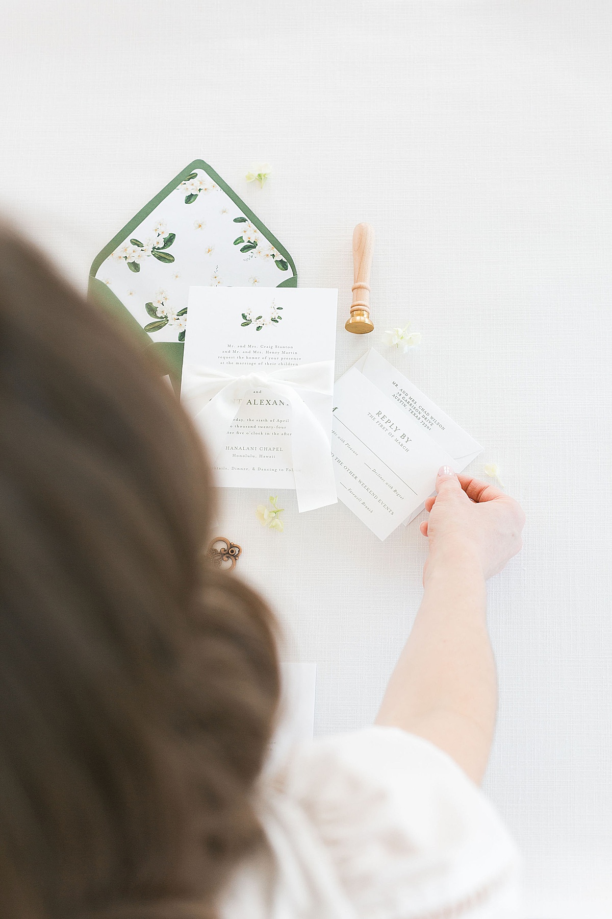 woman arranging wedding invitation pieces on a linen styling mat