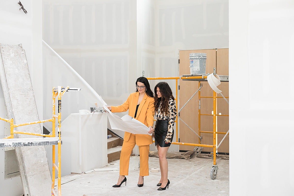 two women interior designers visiting a construction site in progress project holding blueprints